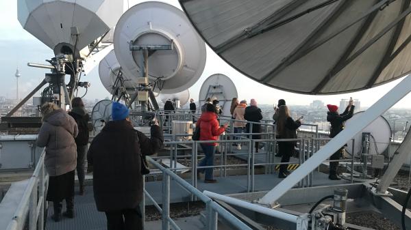 A group of study trip participants standing on the roof among big satellite dishes.