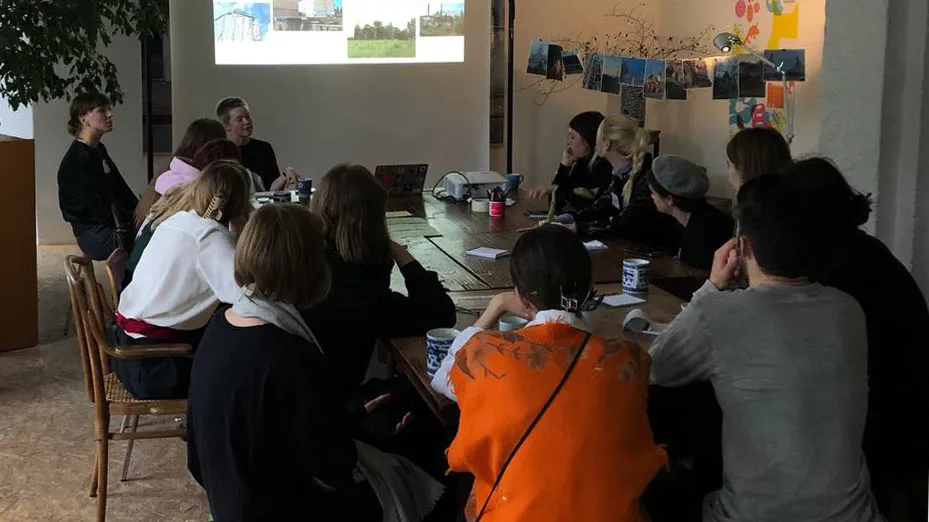 A group of people sitting around the table and listening to a presentation.