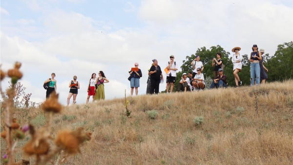 A group of people on a study trip standing at the top of a small hill in the countryside